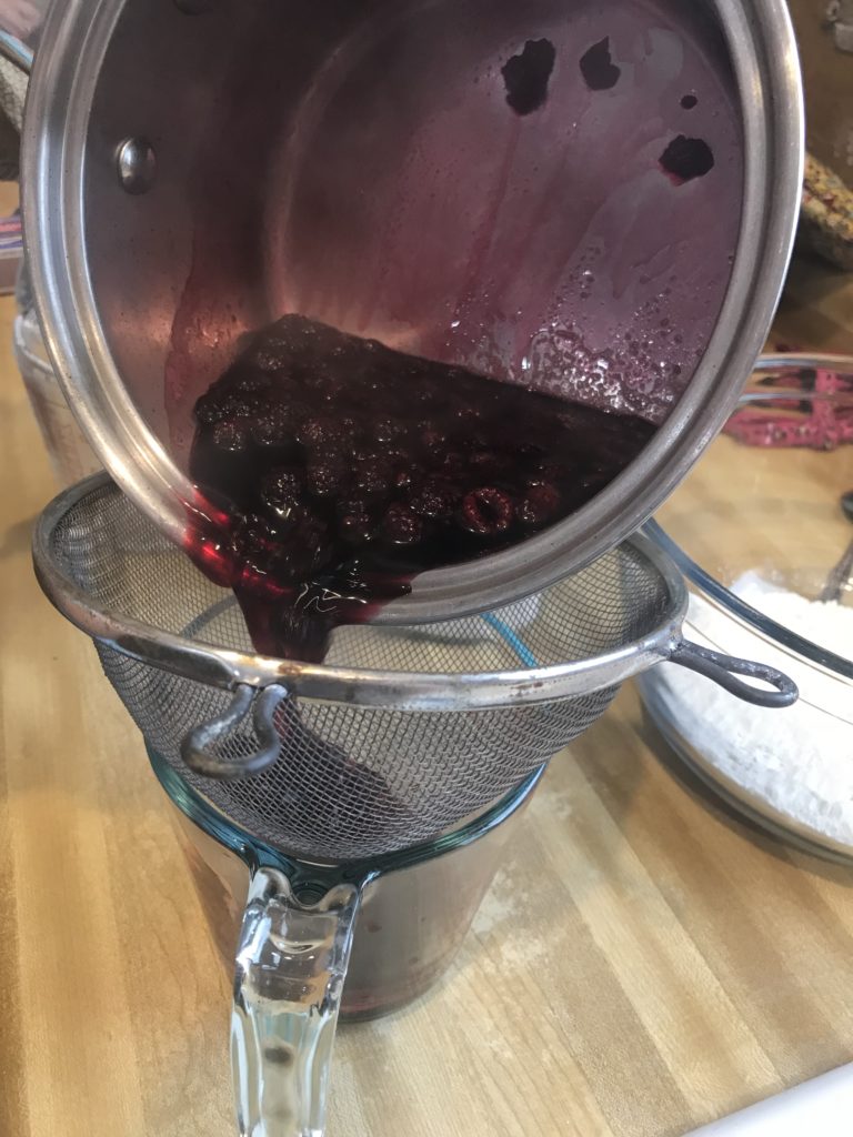 berries and liquid going through a strainer